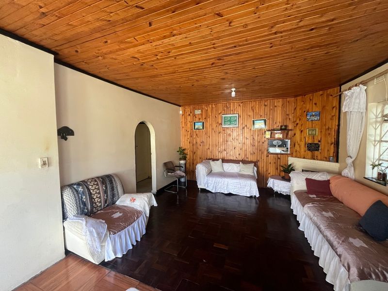 Spacious living room featuring traditional timber ceiling and wall paneling with classic parquet flooring and an arched entryway.