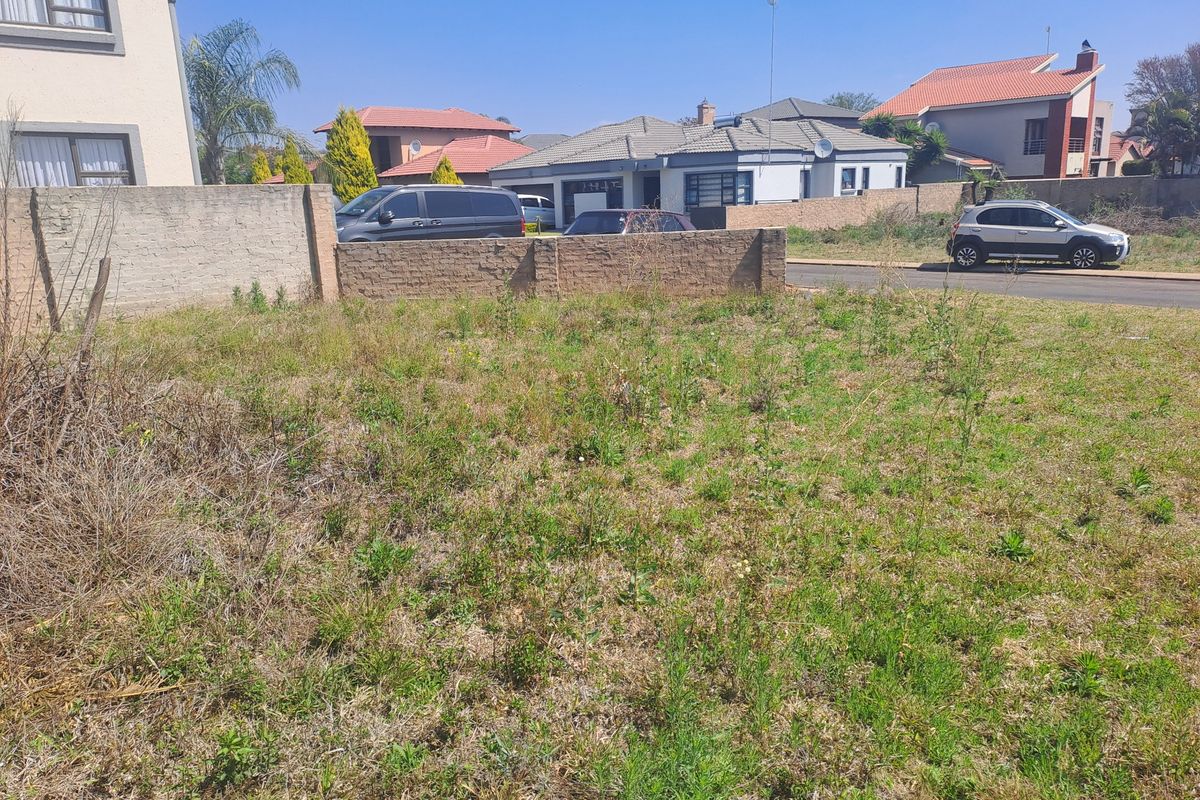 A vacant residential plot featuring a perimeter brick boundary wall, situated in an established suburban neighborhood.