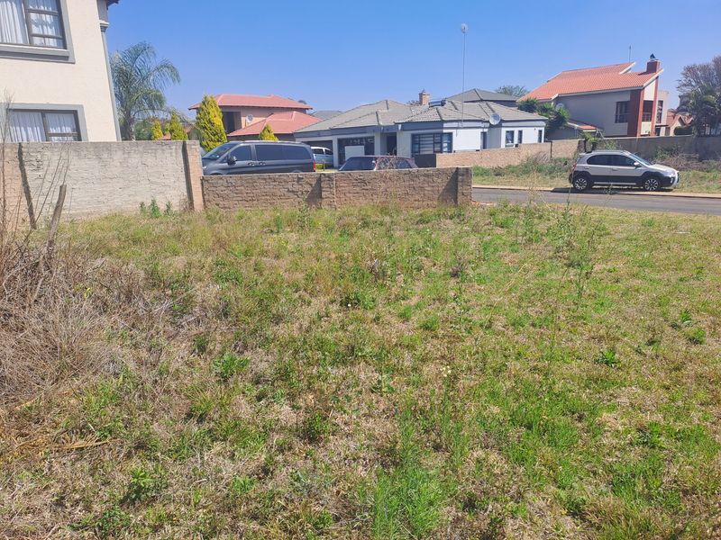 A vacant residential plot featuring a perimeter brick boundary wall, situated in an established suburban neighborhood.