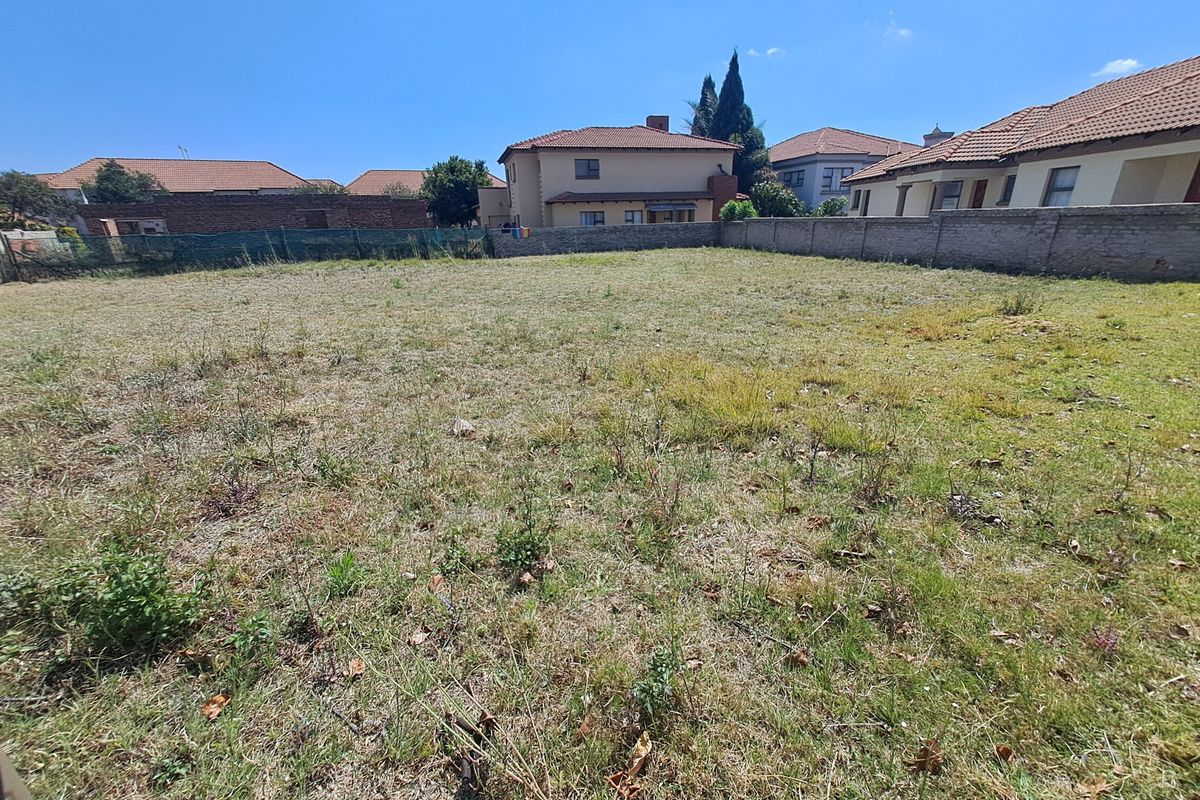A vacant residential plot featuring a level grassed area enclosed by perimeter boundary walls and fencing, situated within an established residential neighborhood.