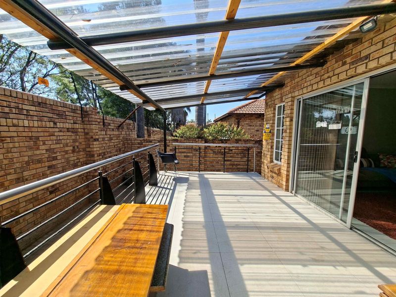 Covered patio area featuring a corrugated roof, facebrick walls, tiled flooring, and a stainless steel balustrade, providing a functional outdoor entertainment space.