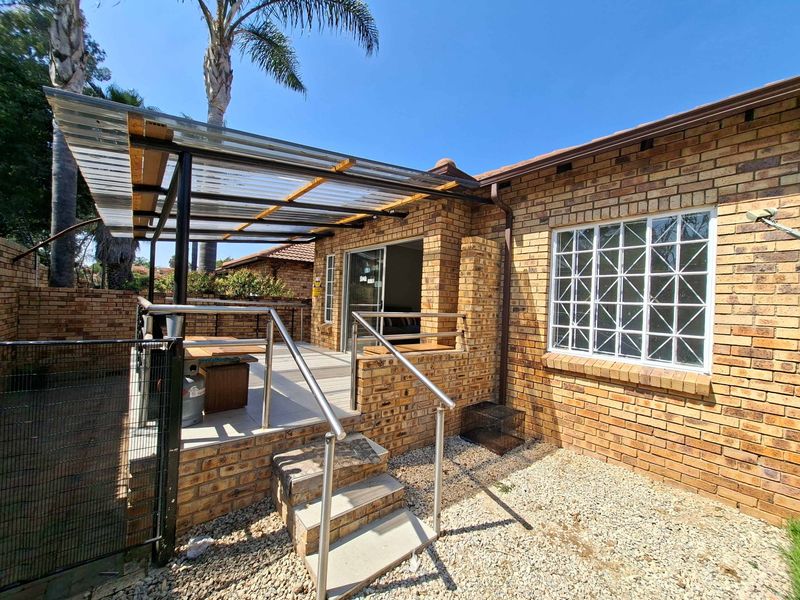 A private outdoor patio area featuring a brick facade, tiled flooring, and a covered roof structure, providing a functional space for outdoor relaxation.
