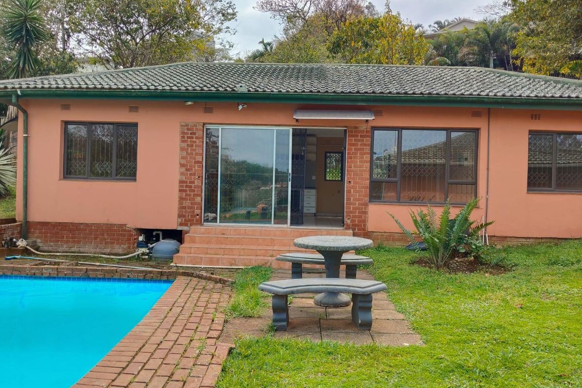 Rear exterior view of the house featuring a swimming pool, brick paved surround, and sliding door access to the living area.