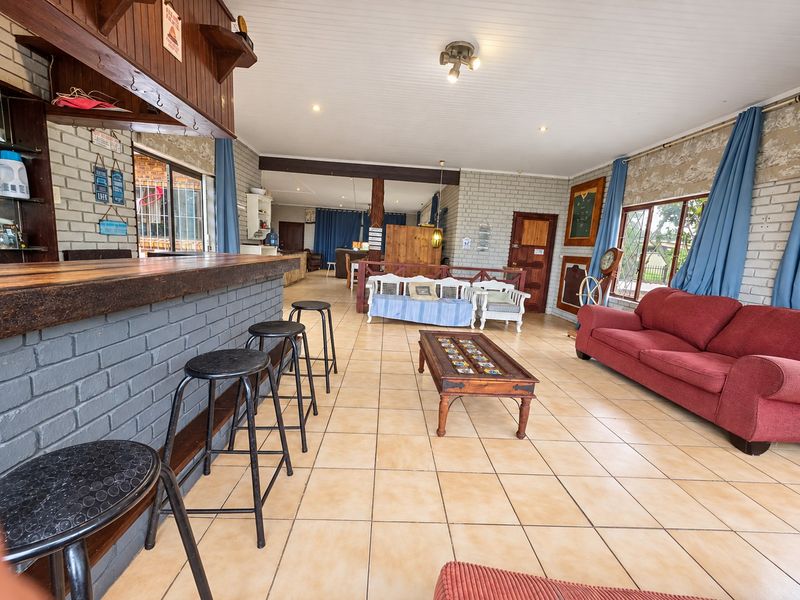 Spacious open-plan living area featuring a built-in bar, tiled flooring, and exposed brick walls, offering a versatile space for entertaining.