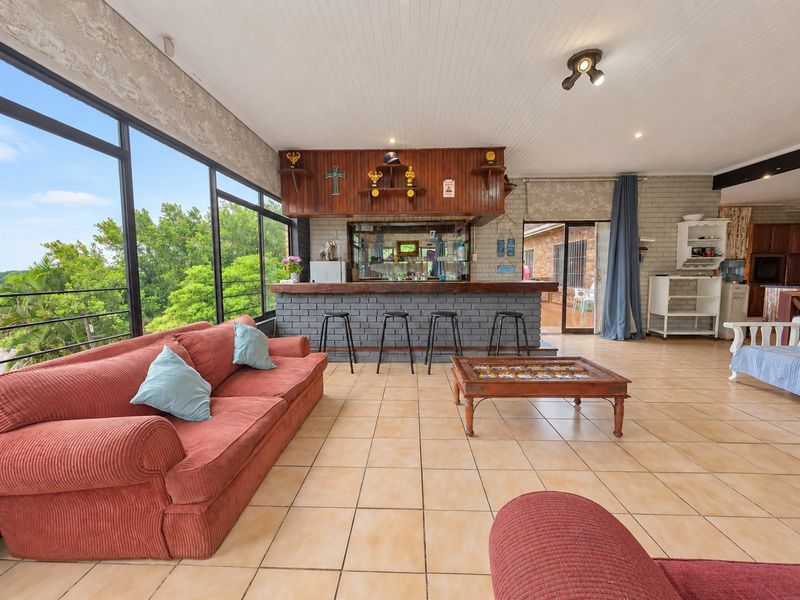 Spacious entertainment area featuring a built-in brick bar, tiled flooring, and large glass sliding doors offering natural light and garden views.