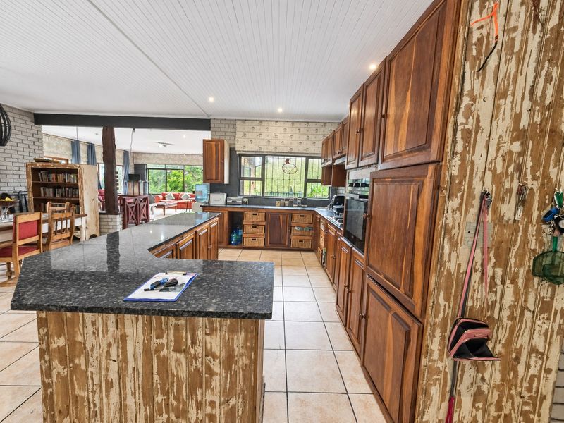 Spacious open-plan kitchen featuring granite countertops, extensive wooden cabinetry, and integrated oven, flowing into the adjacent living and dining areas.