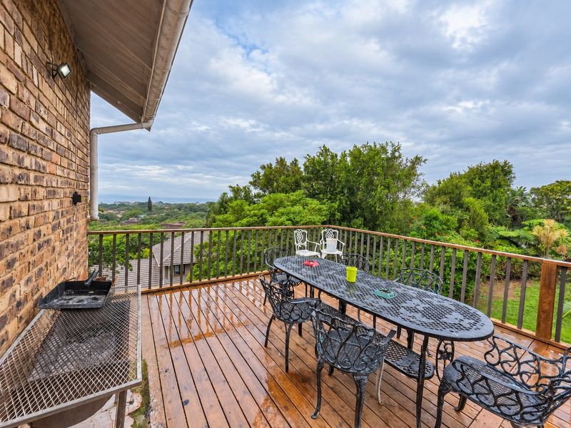 Elevated wooden balcony featuring a timber balustrade, brick wall finish, and scenic views, providing an ideal space for outdoor entertaining.