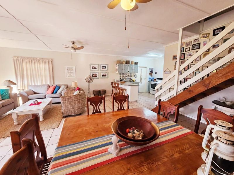 Open-plan living and dining area featuring a kitchen island, tiled flooring, and a staircase leading to the upper level.