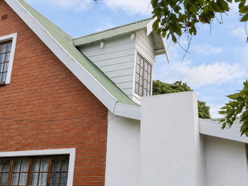 A view of the rear exterior featuring a classic brick facade, corrugated metal roofing, and a prominent dormer window.