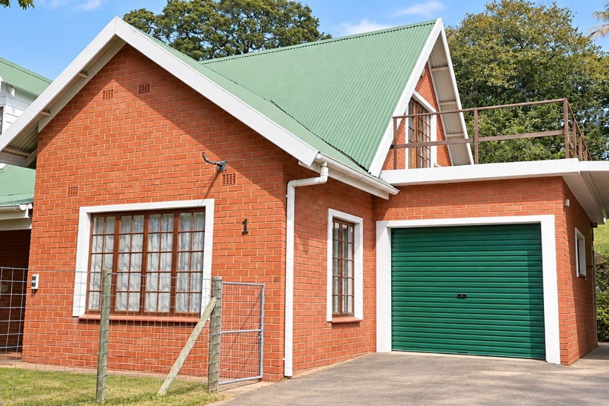 Front view of a charming red brick house featuring a green corrugated metal roof, a single garage, and an attached carport.