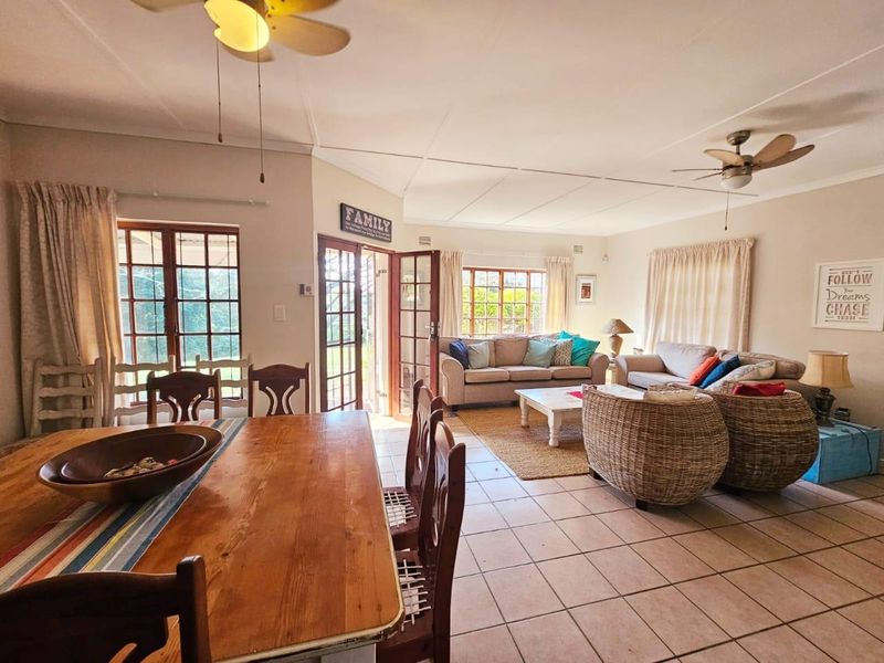 Spacious open-plan living and dining area featuring tiled flooring, ceiling fans, and multiple sets of timber-framed french doors leading to the exterior.