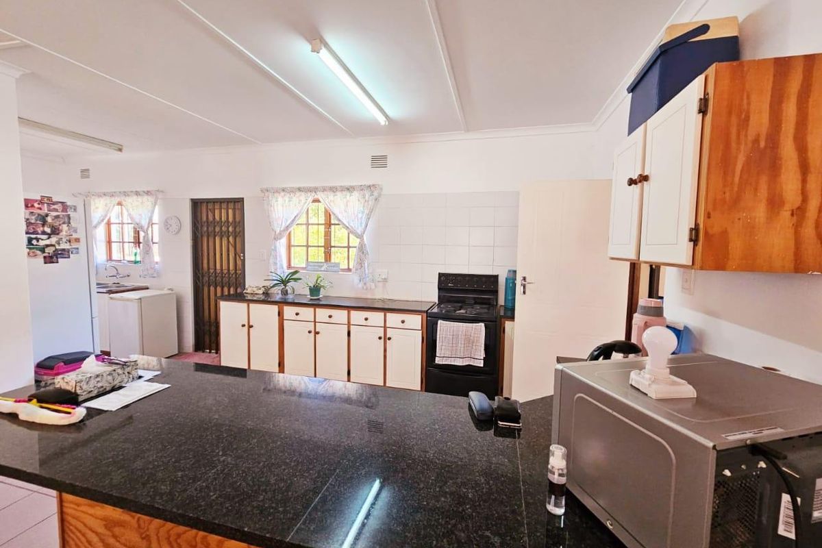 Functional kitchen featuring granite countertops, ample built-in cabinetry, and a tiled backsplash, offering a practical layout with direct access to adjacent areas.