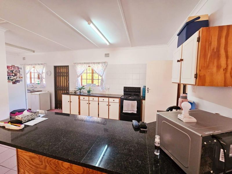 Functional kitchen featuring granite countertops, ample built-in cabinetry, and a tiled backsplash, offering a practical layout with direct access to adjacent areas.