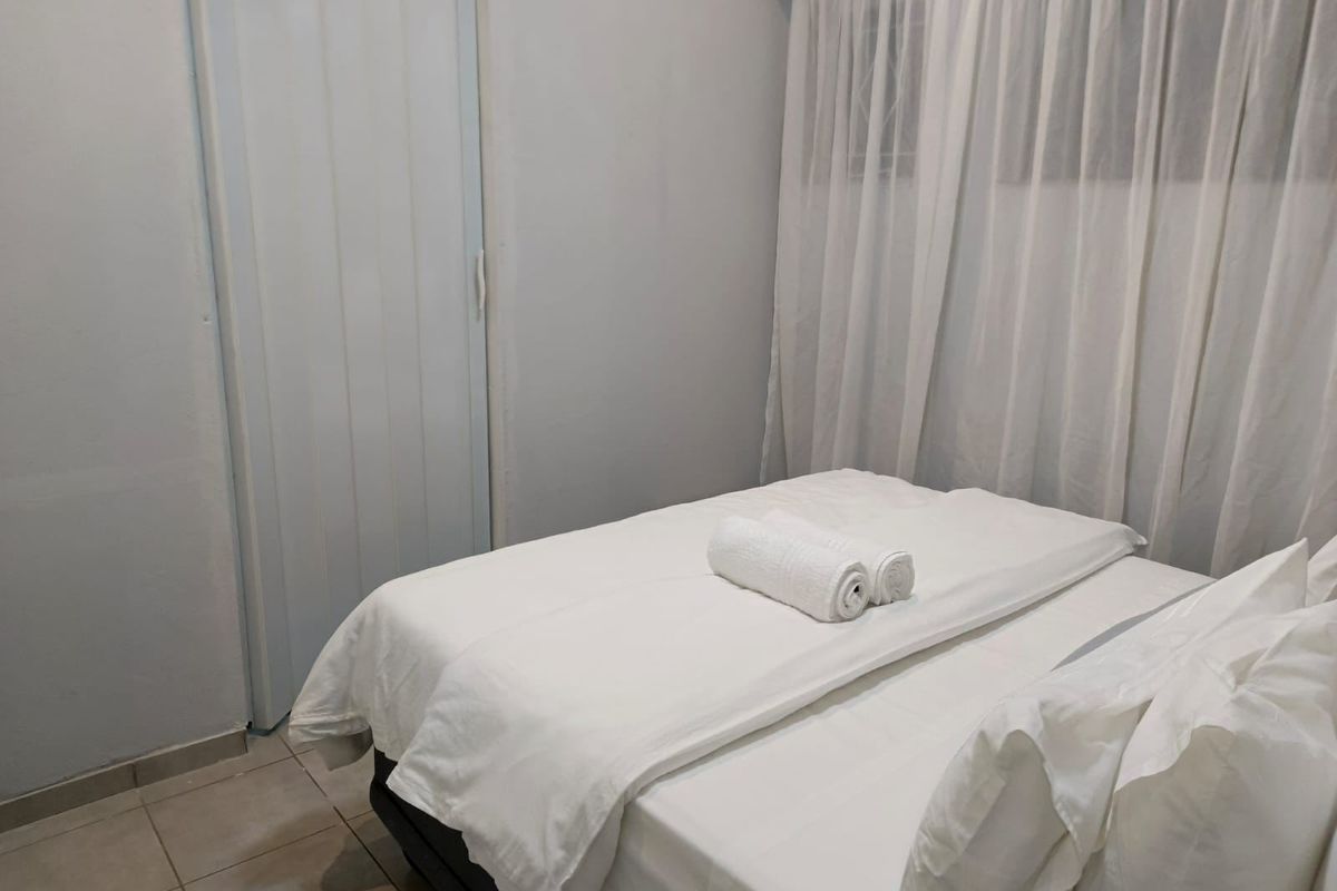 A simple bedroom featuring tiled flooring and a folding door, providing a functional and neutral living space.