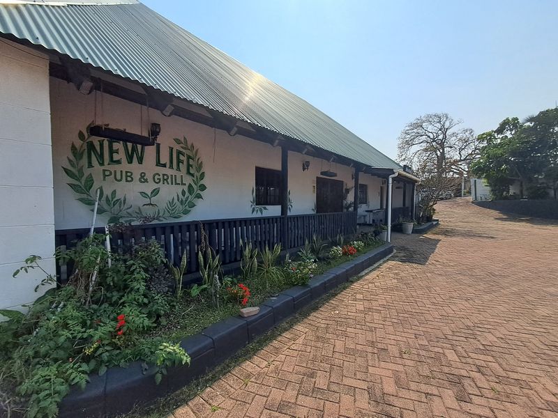 Exterior view of a commercial pub and grill featuring a covered veranda, corrugated metal roof, and paved driveway access.