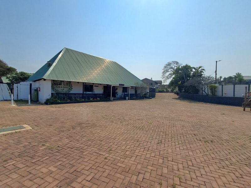 Front view of a commercial pub and grill property featuring a large paved parking area and a building with a prominent metal roof.