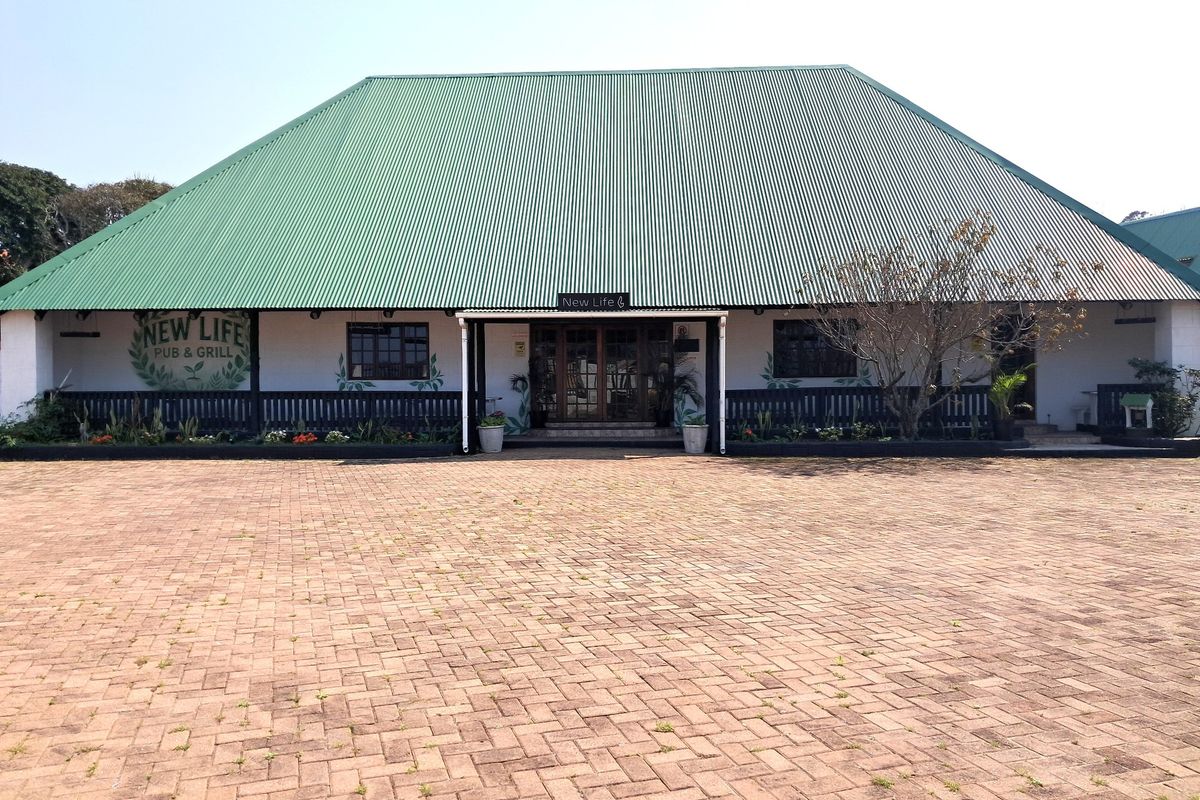 Front elevation of a commercial pub and grill building featuring a large corrugated metal roof, paved forecourt, and timber entrance details.