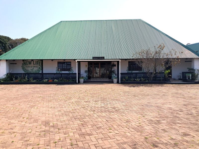 Front elevation of a commercial pub and grill building featuring a large corrugated metal roof, paved forecourt, and timber entrance details.