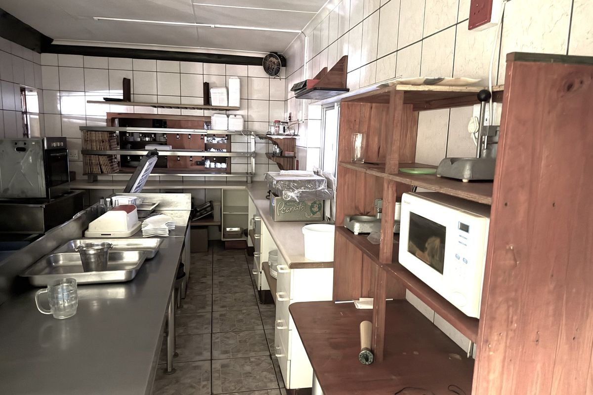Commercial kitchen area featuring stainless steel prep surfaces, tiled wall finishes, and built-in shelving units suitable for food preparation and storage.