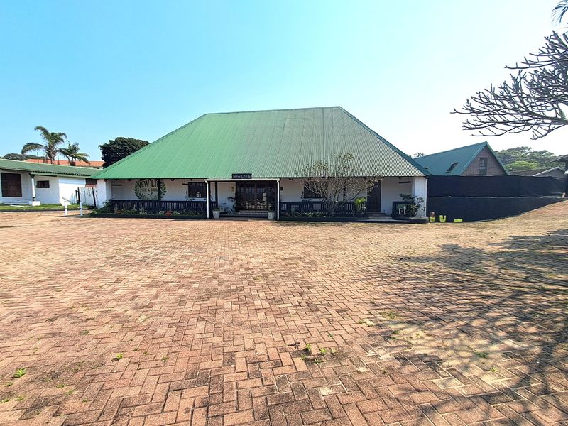 Front view of a commercial pub and grill property featuring a large paved parking area and a covered veranda entrance.