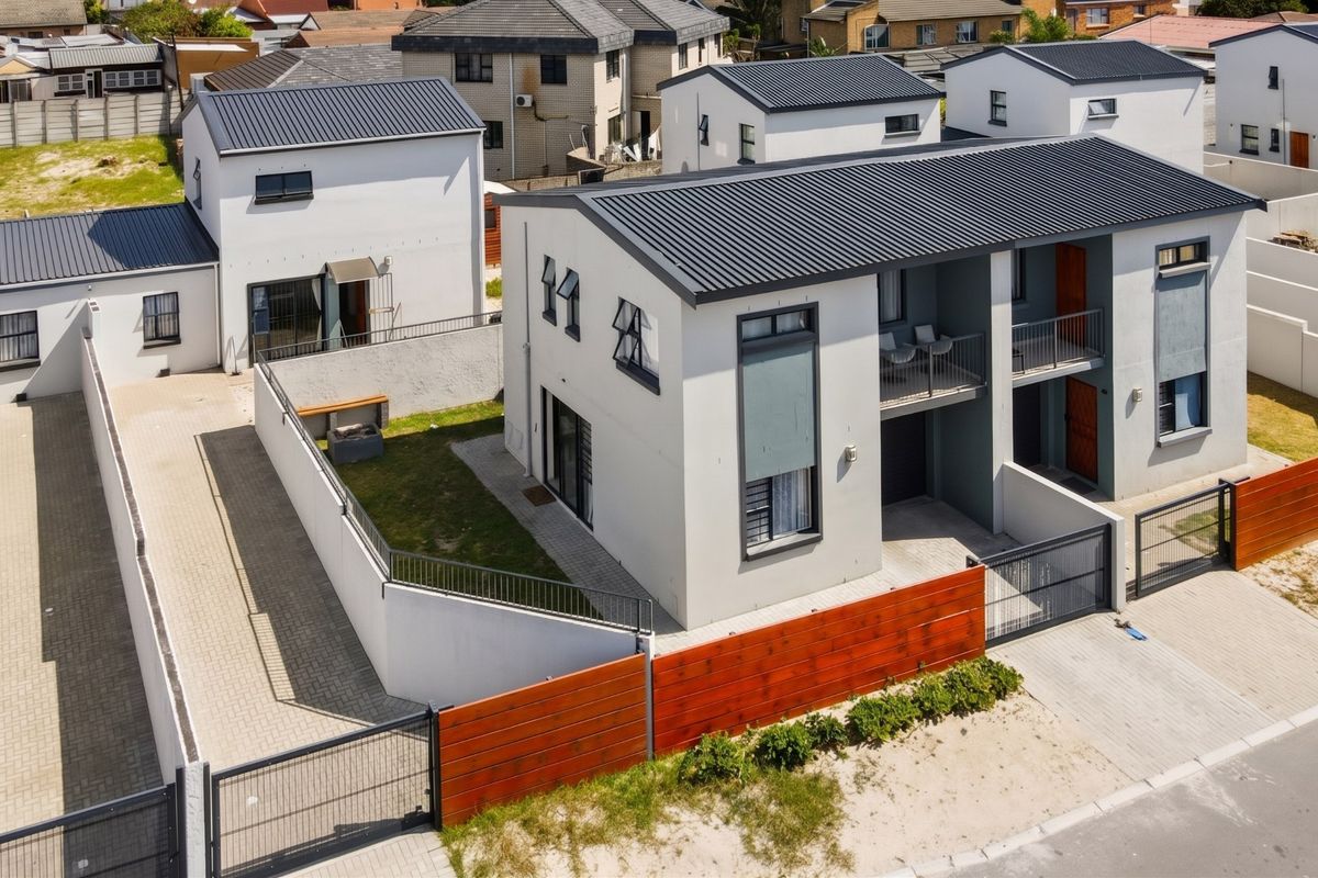 Aerial view of a modern residential complex featuring contemporary architecture, paved driveways, secure boundary walls, and private balconies.