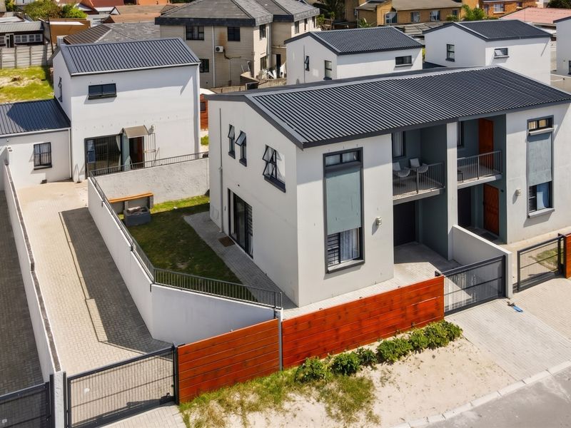 Aerial view of a modern residential complex featuring contemporary architecture, paved driveways, secure boundary walls, and private balconies.