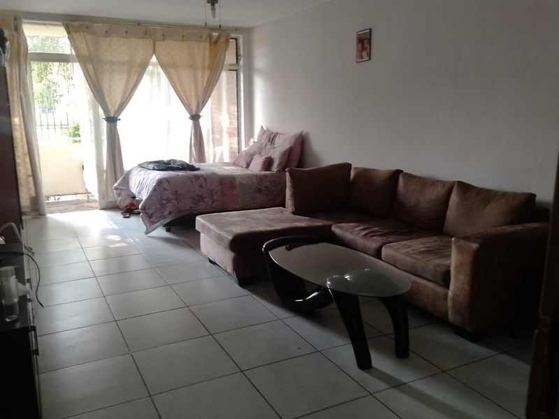 Open plan living and sleeping area featuring tiled flooring and a large sliding glass door providing access to an outdoor space.