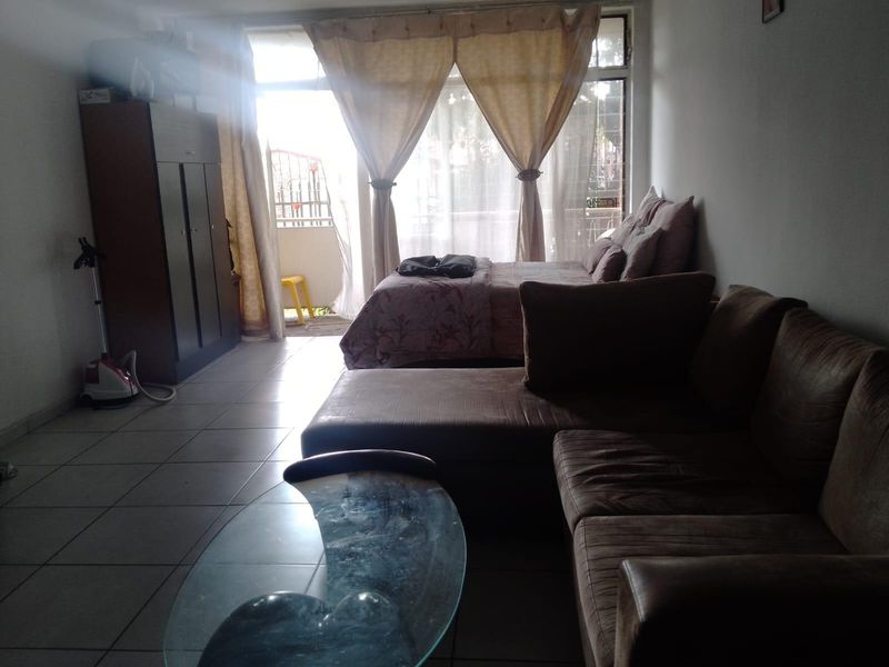 Open plan living and sleeping area featuring tiled flooring and direct access to a balcony through a large sliding glass door.