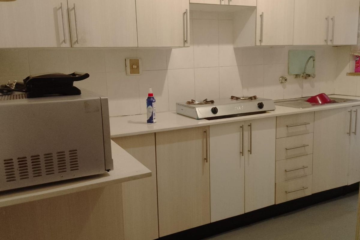 A functional kitchen featuring light-toned laminate cabinetry, a gas cooktop, a stainless steel sink, and a tiled backsplash.