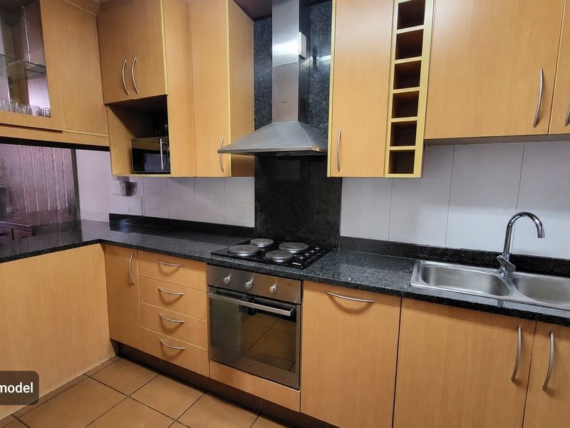 A functional kitchen featuring light wood-finish cabinetry, dark granite countertops, integrated stainless steel appliances, and a double bowl sink.
