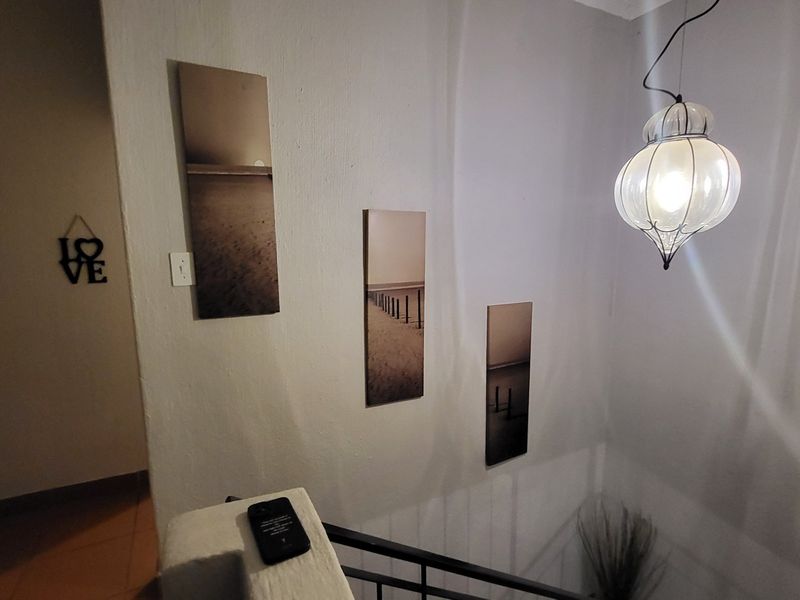 A hallway area featuring a decorative pendant light fixture and a staircase railing.