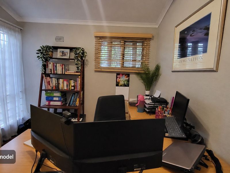 A functional home office space featuring neutral wall tones, wooden venetian blinds, and decorative cove cornicing.