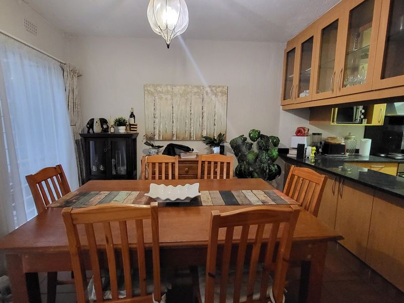 Open-plan dining and kitchen area featuring wooden cabinetry, granite countertops, and a functional layout suitable for family living.