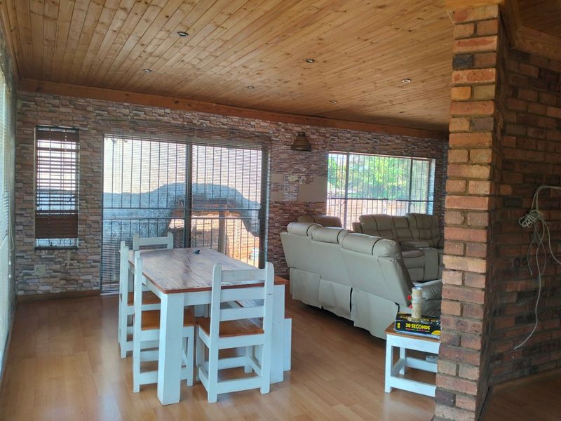 Open plan living and dining area featuring timber ceilings, exposed brickwork, and sliding glass doors leading to the exterior.