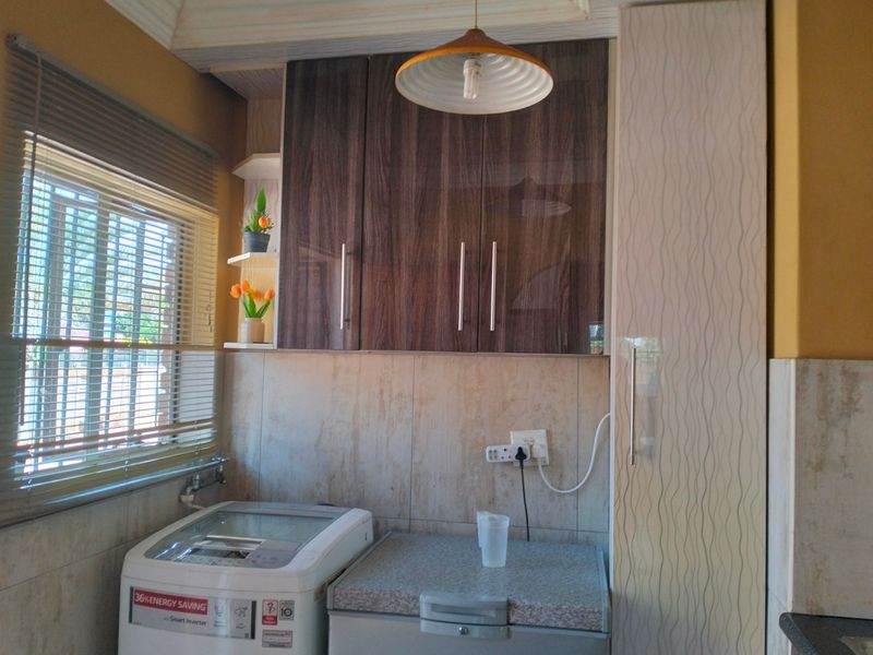 A functional laundry area featuring built-in cabinetry, tiled splashback, and a window with venetian blinds.