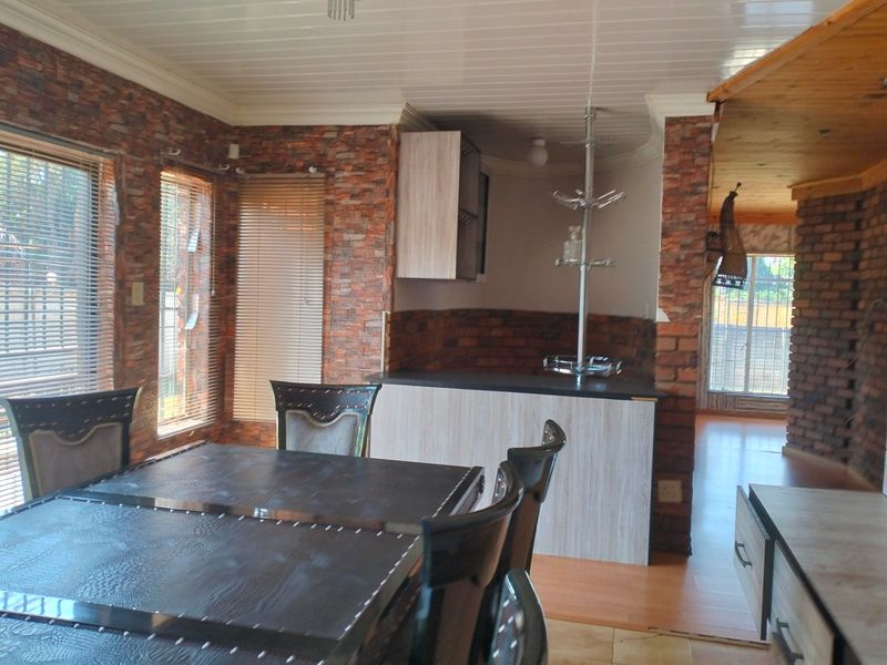 Open plan living and dining area featuring brick veneer wall accents, laminate flooring, and built-in cabinetry with a breakfast bar.