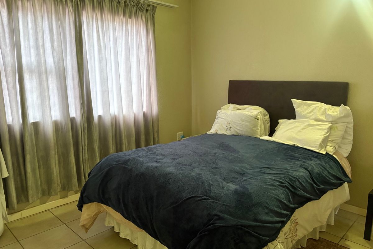 A functional bedroom featuring tiled flooring and large windows with installed curtain rails, providing a neutral base for personalization.