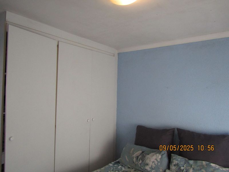 A bedroom featuring a built-in wardrobe with white doors and a blue accent wall.
