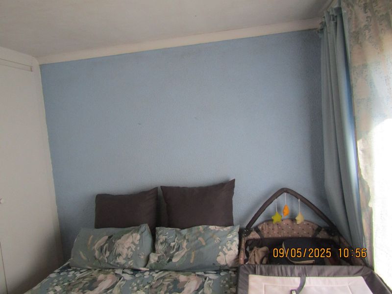 A bedroom featuring a built-in cupboard and blue textured wall finish, providing a functional space for rest.