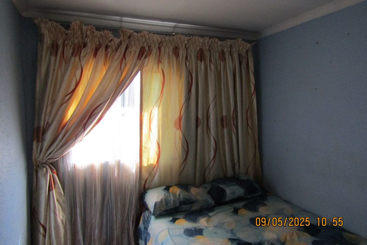 A bedroom featuring a window with a curtain rail, painted walls, and standard ceiling finish.