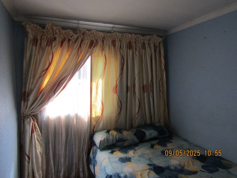 A bedroom featuring a window with a curtain rail, painted walls, and standard ceiling finish.