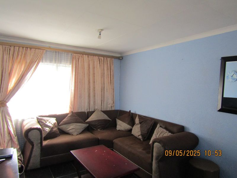 A living room featuring blue walls, a large window with curtain rod, and cove cornicing.