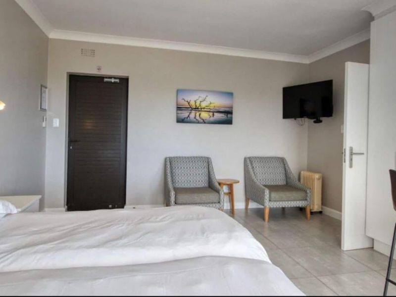 A well-maintained bedroom featuring tiled flooring, built-in wardrobe storage, and neutral wall finishes with cove cornicing.