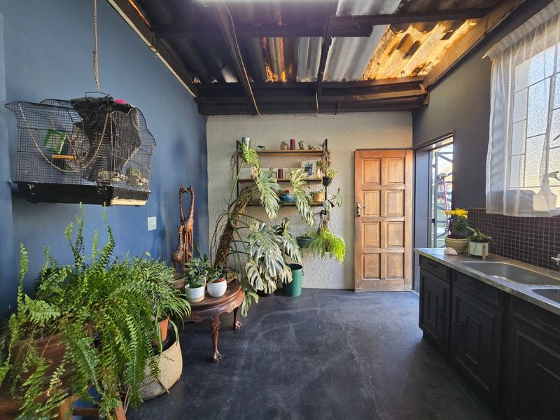 A utility scullery area featuring built-in cabinetry, a stainless steel sink, and an exposed roof structure with natural light entry.