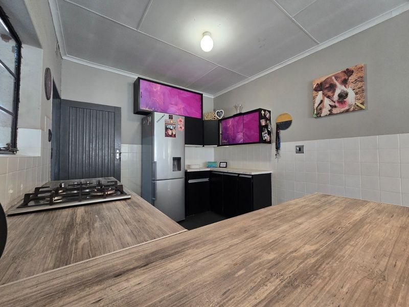 Kitchen featuring a gas hob, laminate countertops, and custom cabinetry with a tiled splashback, offering a functional workspace with potential for modern updates.