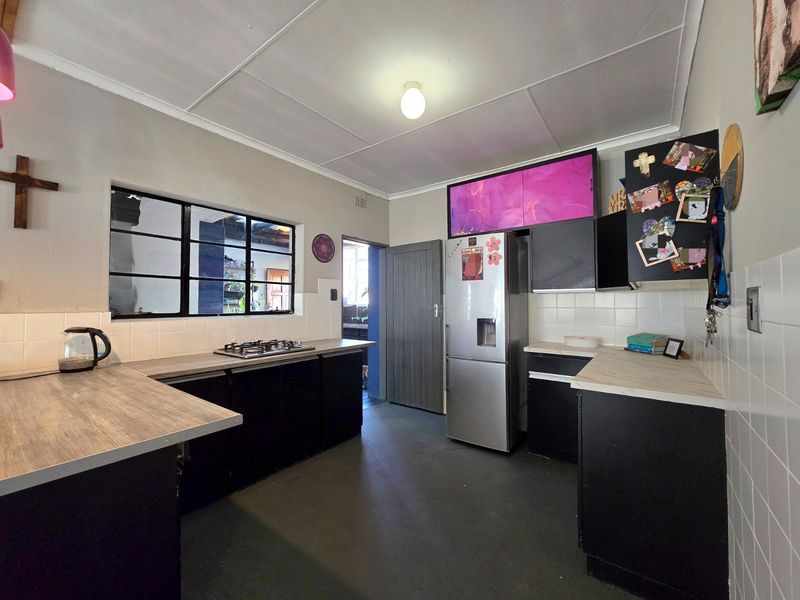 Functional kitchen featuring dark cabinetry, laminate countertops, a gas hob, and a tiled backsplash, with direct access to an adjacent utility area.