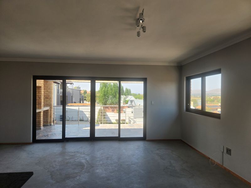 Spacious, empty living area featuring polished concrete floors, large sliding glass doors leading to a patio, and modern aluminium window frames with scenic views.