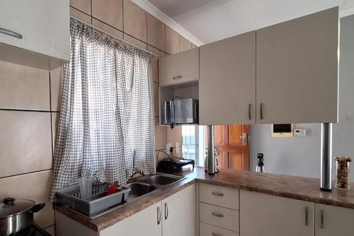 Functional kitchen featuring light-toned cabinetry, laminate countertops, a double basin sink, and a tiled backsplash with a convenient breakfast bar area.