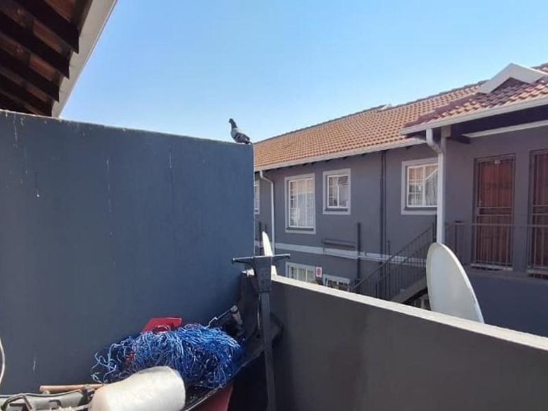 A functional balcony area overlooking the apartment complex courtyard, featuring a solid privacy wall and metal railing.