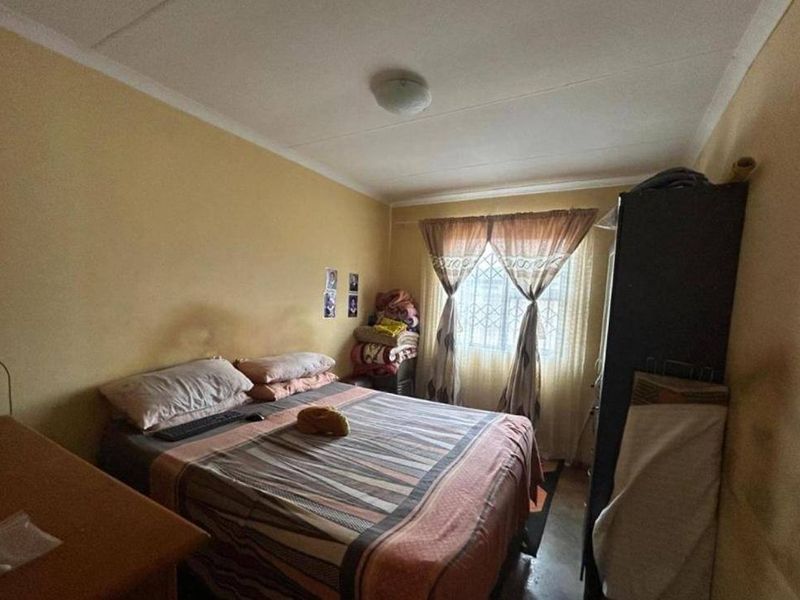 A compact bedroom featuring a window with curtains and a central ceiling light fixture.